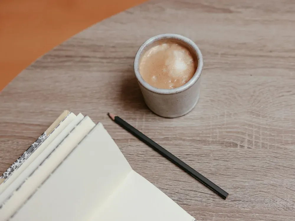 Carnet de notes, stylo et tasse de café sur un bureau en bois
